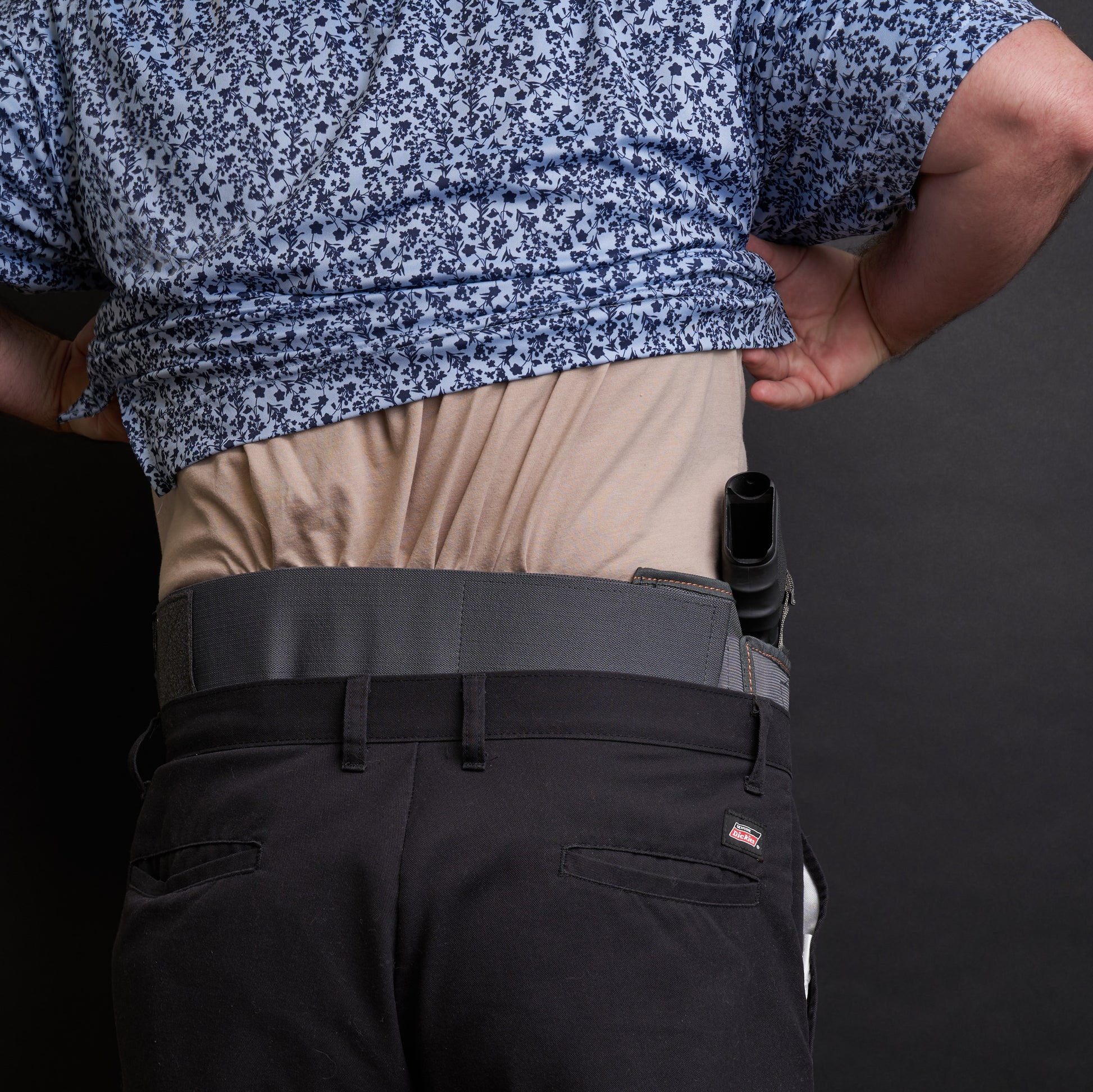 Back view of a man wearing the VNSH grey waist belt extender 20 inches attached to the VNSH grey Holster with a gun in it