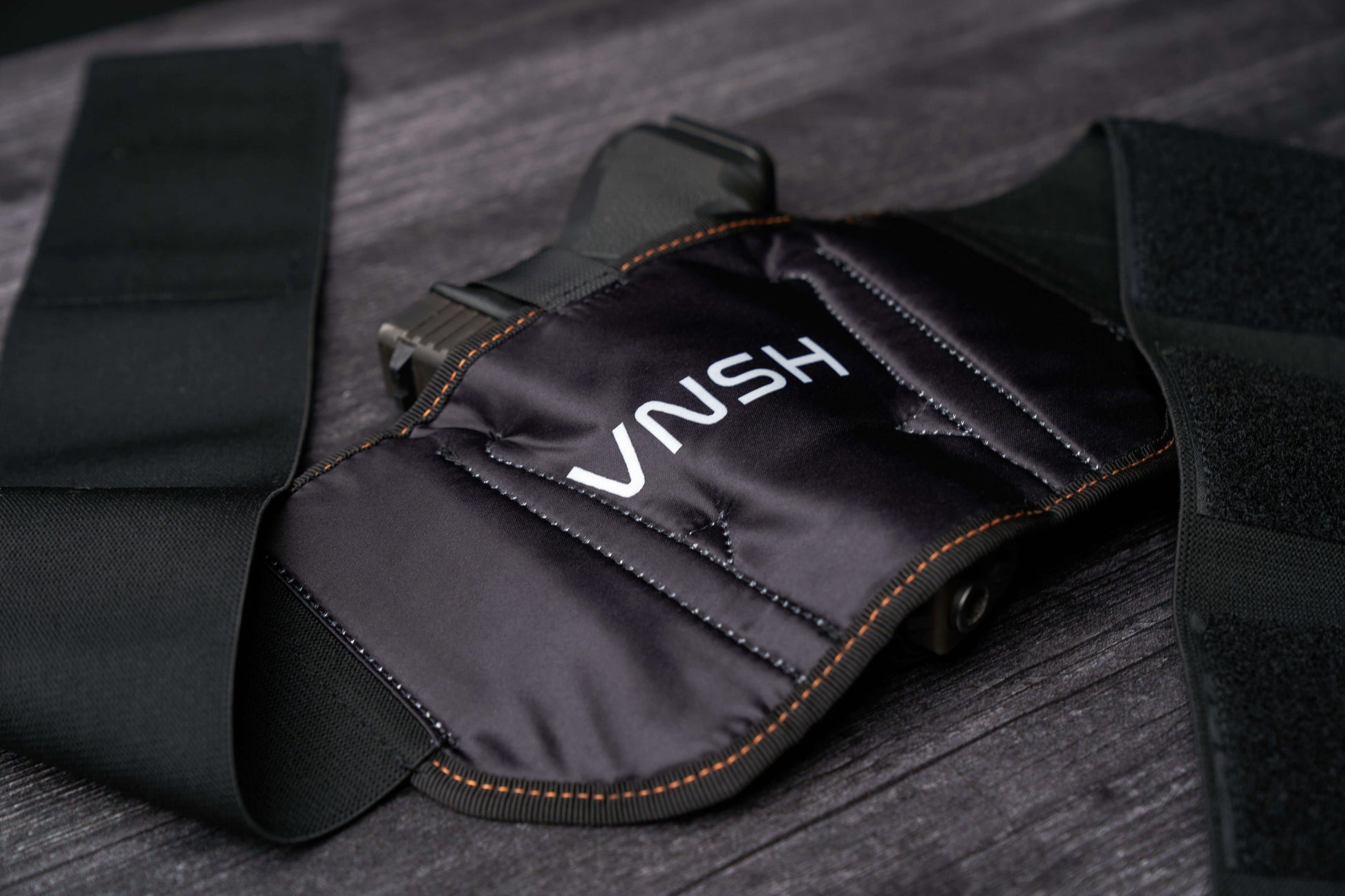 A close up view of the VNSH Black Holster showing the inner side with its logo and a gun in it
